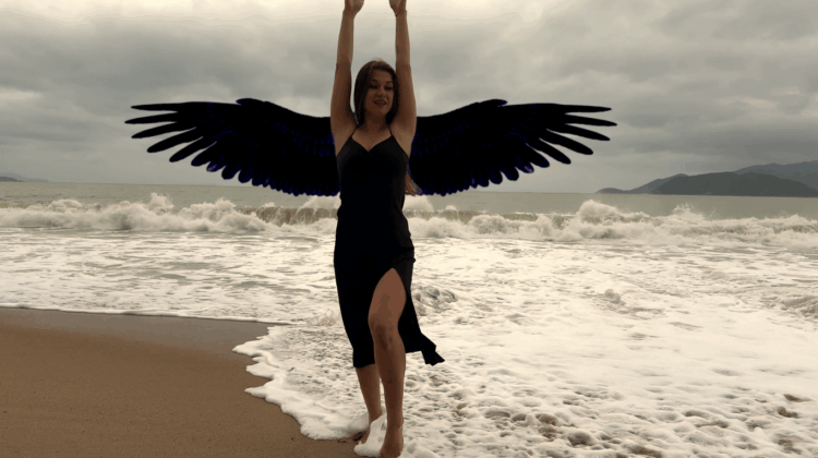 Lisa in a black dress on the beach of Nha Trang Vietnam with large black wings