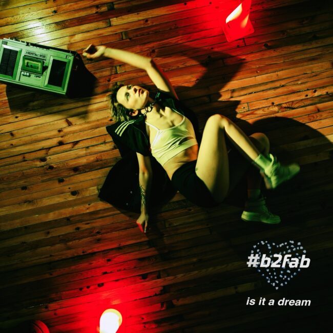 Lily lying on the floor of a gym with red pilons and a gettoblaster